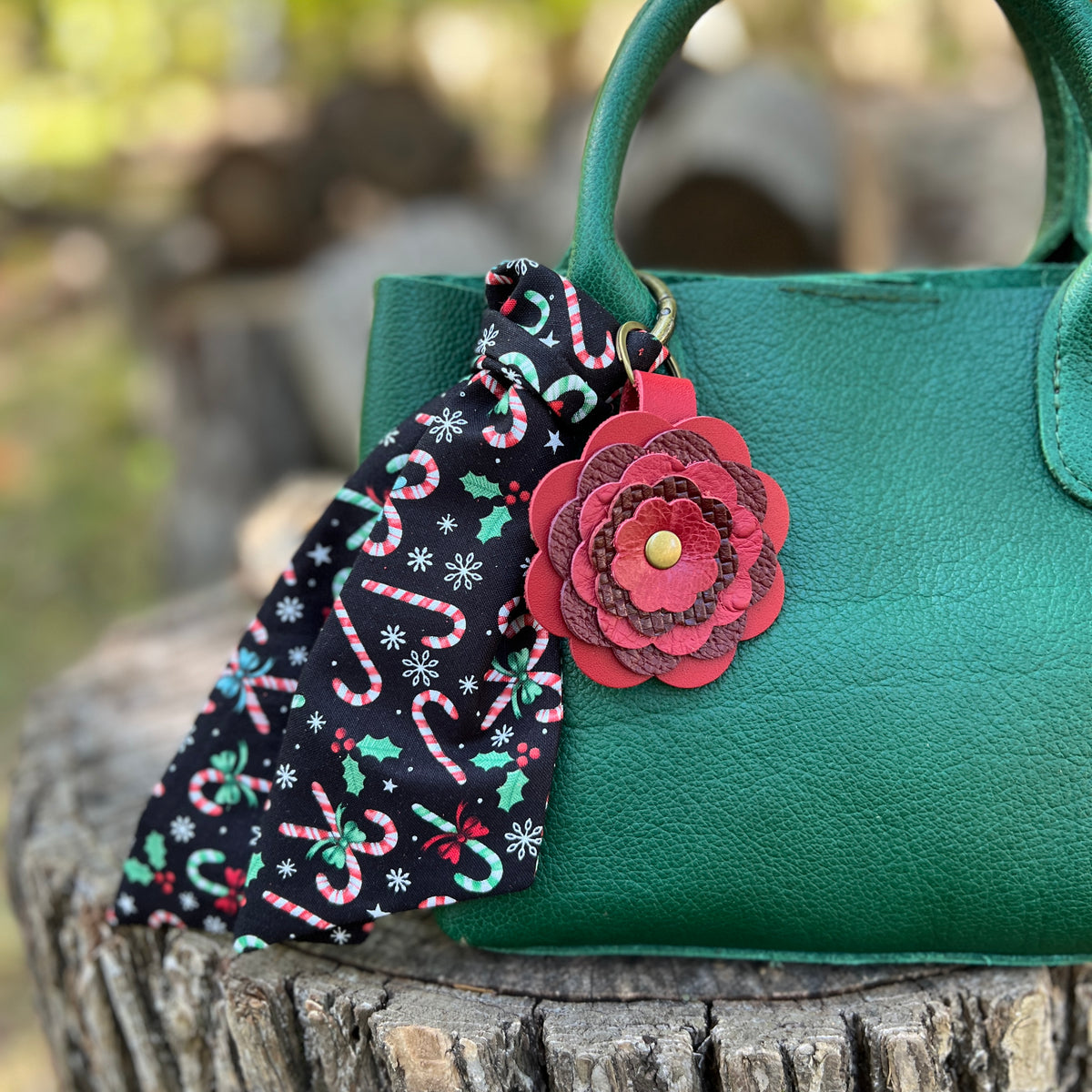 red leather flower bag charm with candy cane print christmas scarf on green bag