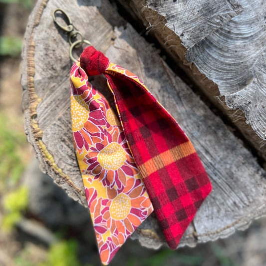 Keychain with floral and plaid designs hanging on a wooden surface