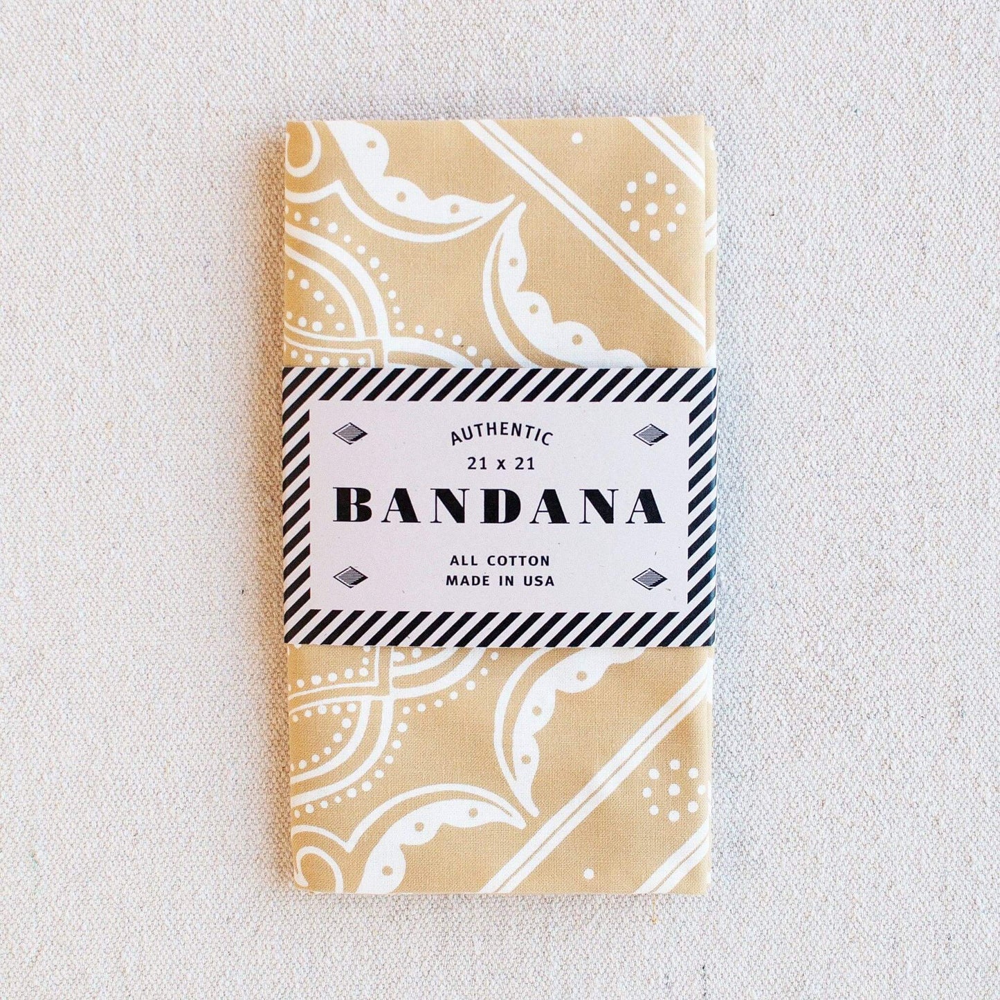 Packaged bandana with beige and white pattern on a light gray background