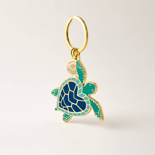 Gold and blue turtle-shaped pendant on a beige background