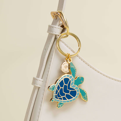Turtle keychain attached to a white strap on a beige background