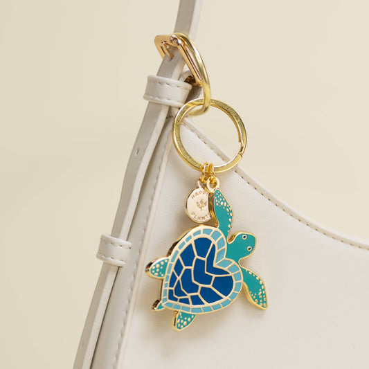 Turtle keychain attached to a white strap on a beige background