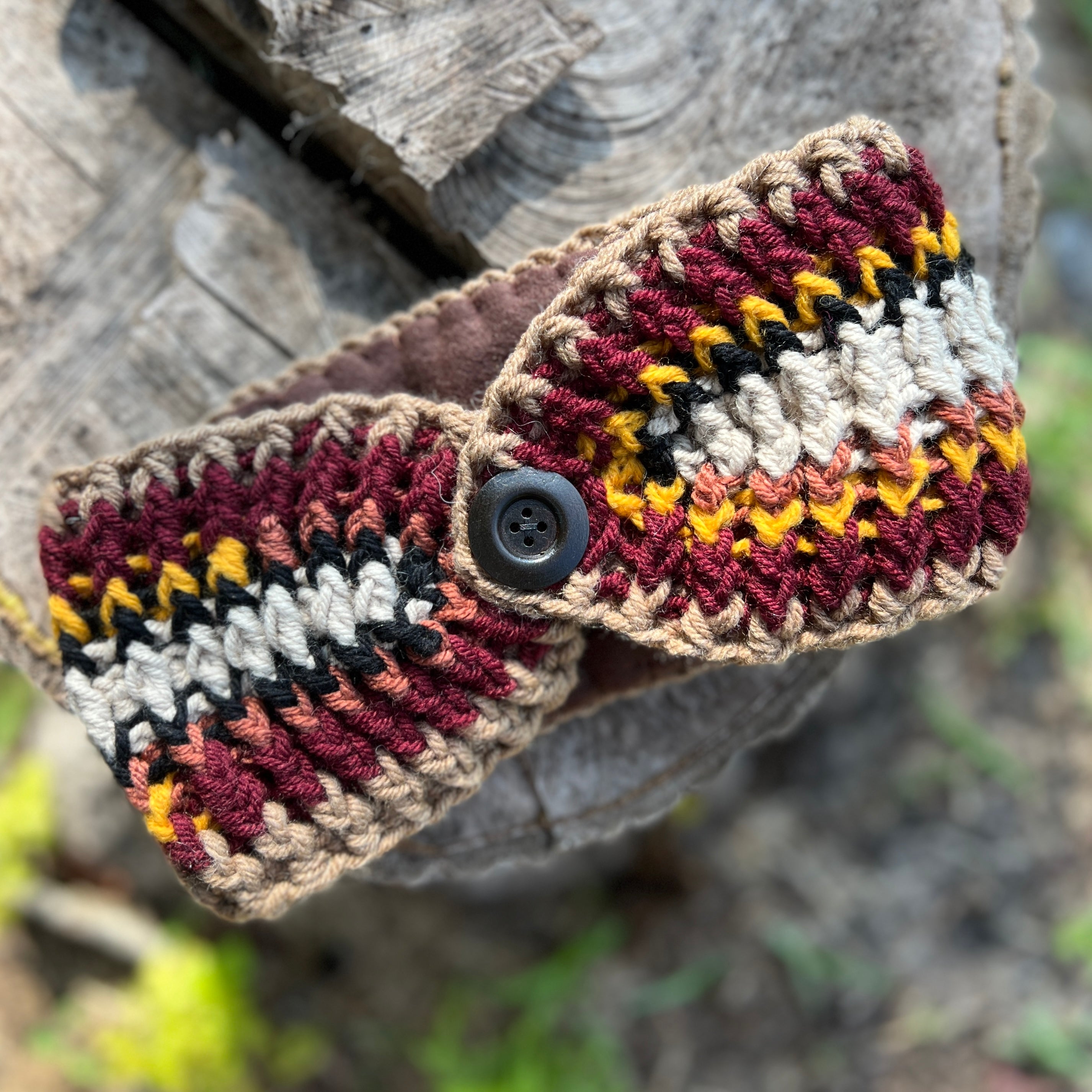 Crocheted headband with a button on a wooden surface