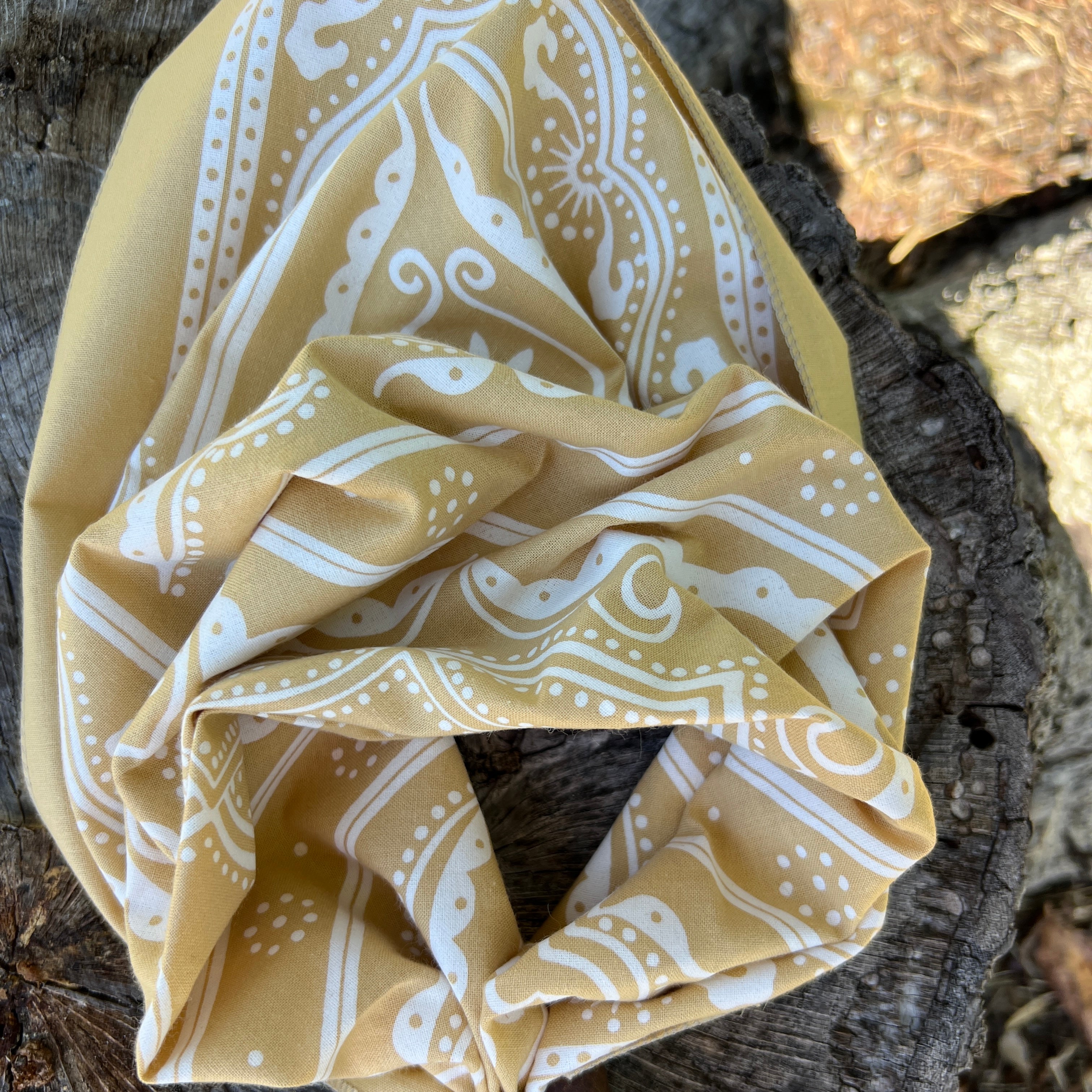 Packaged bandana with beige and white pattern on a light gray background