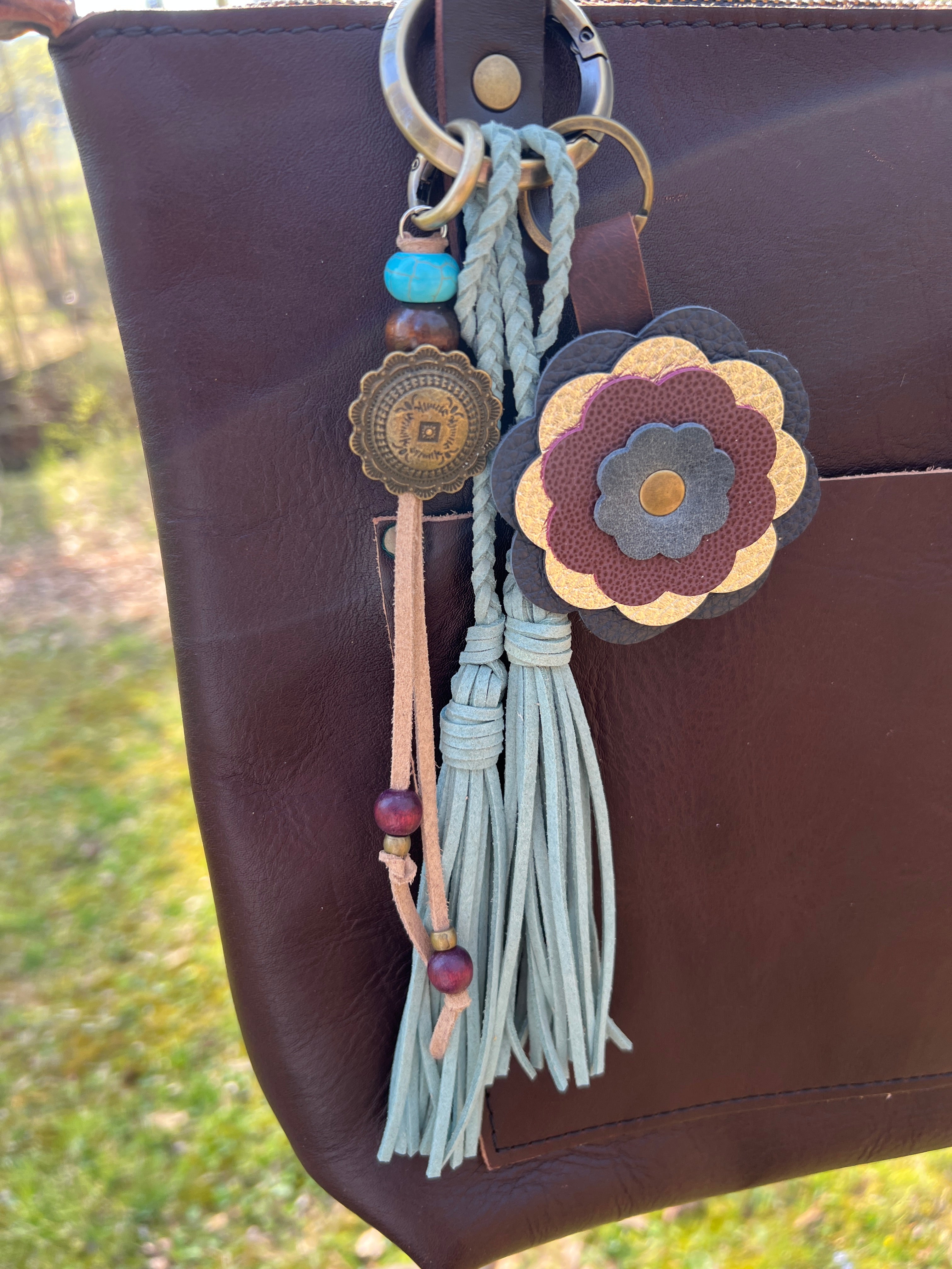 Decorative keychain with flowers and tassels on a brown leather bag.