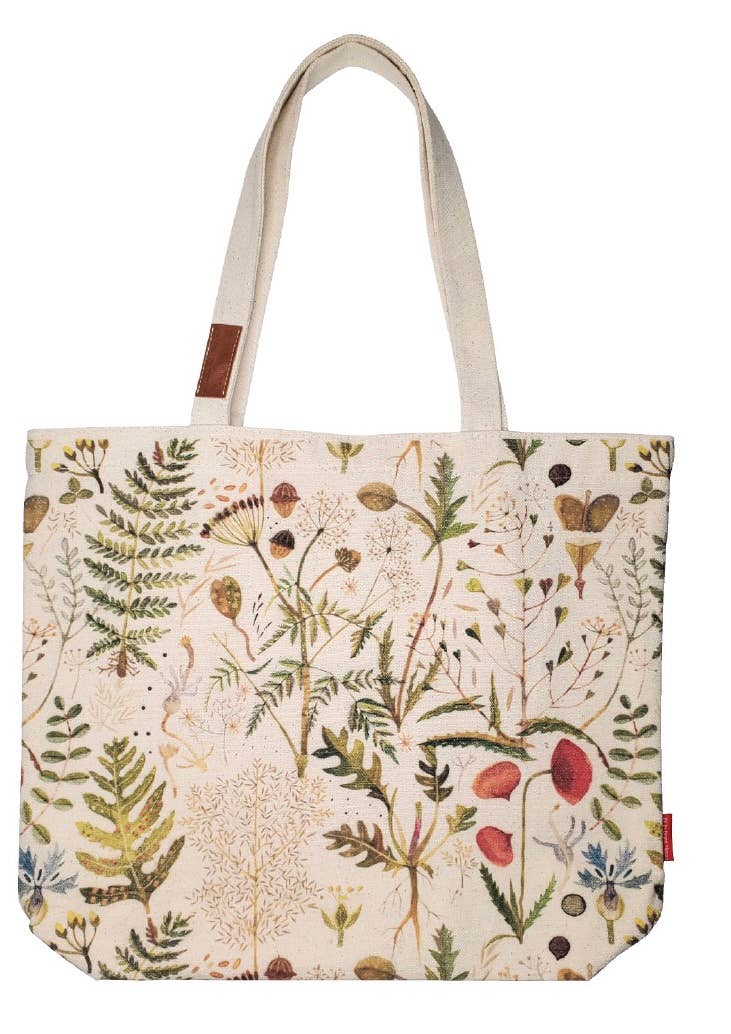 A canvas tote bag with a detailed botanical and wildflower print on a cream background, featuring natural beige shoulder straps and a small brown leather brand patch.