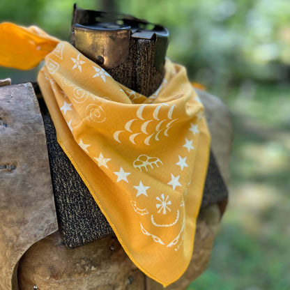Yellow bandana with white patterns draped over a wooden object against a blurred natural background