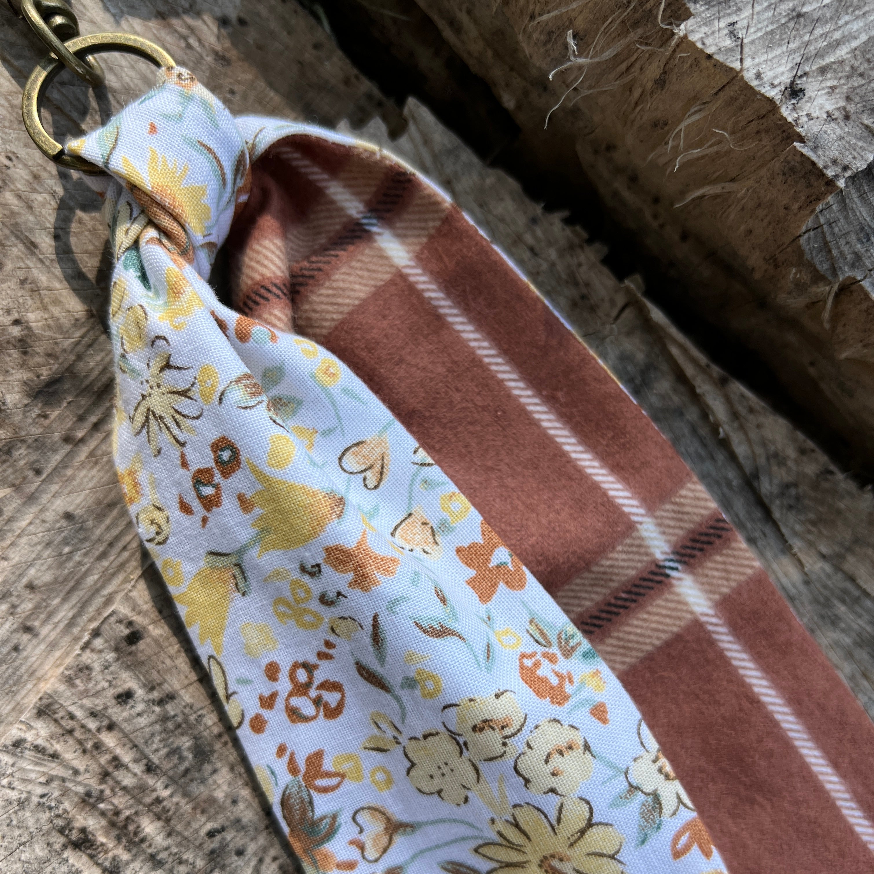Fabric swatch with floral pattern and plaid design on a wooden surface
