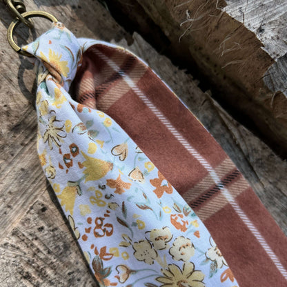 Fabric swatch with floral pattern and plaid design on a wooden surface