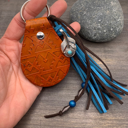 Southwestern Style Leather Key Fob with TasselGenuine leather key fob with southwestern embossed pattern. Faux suede tassel in blue and dark brown with feather charm. Key fob has been embossed and dyed by hand. 3" long leather fob with 5" tassel