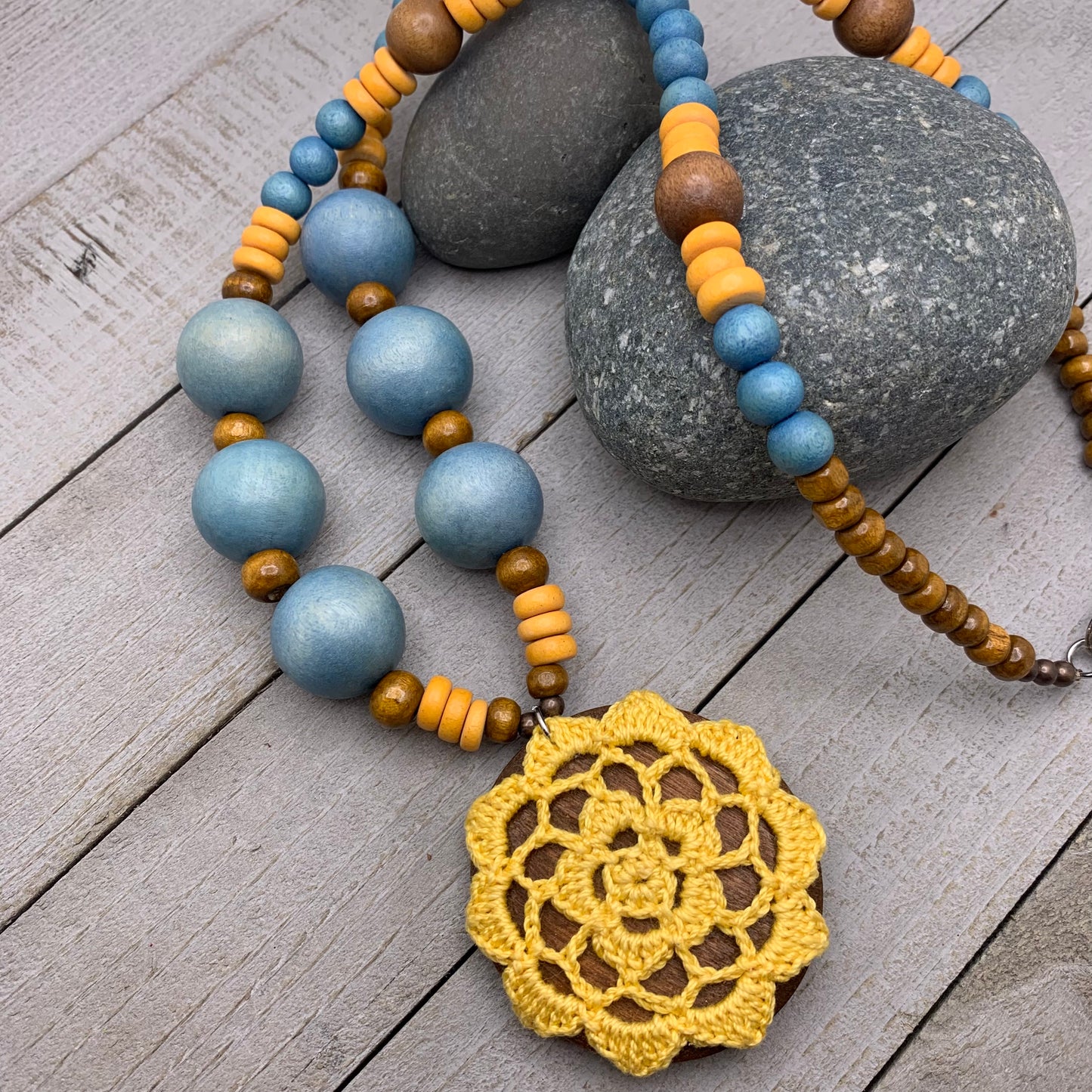 long wooden bead necklace with yellow crocheted pendant